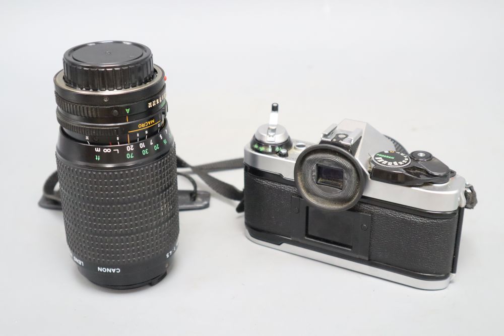 A cased Canon AE-1 programme camera with a 50mm lens, together with a 75-200mm zoom lens, also Canon accessories